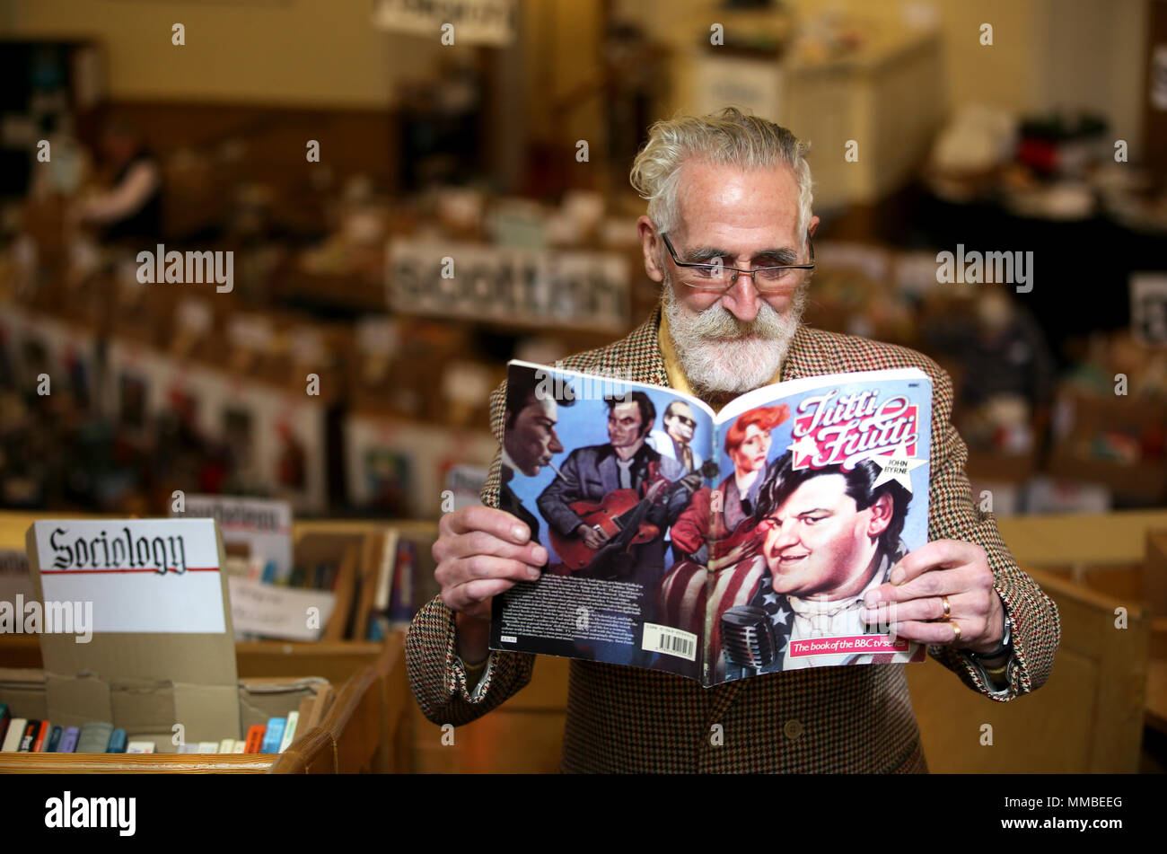 Author, playwright and artist John Byrne takes a closer look at a rare edition of his play Tutti Frutti, at the Christian Aid George Street book sale in Edinburgh. Stock Photo