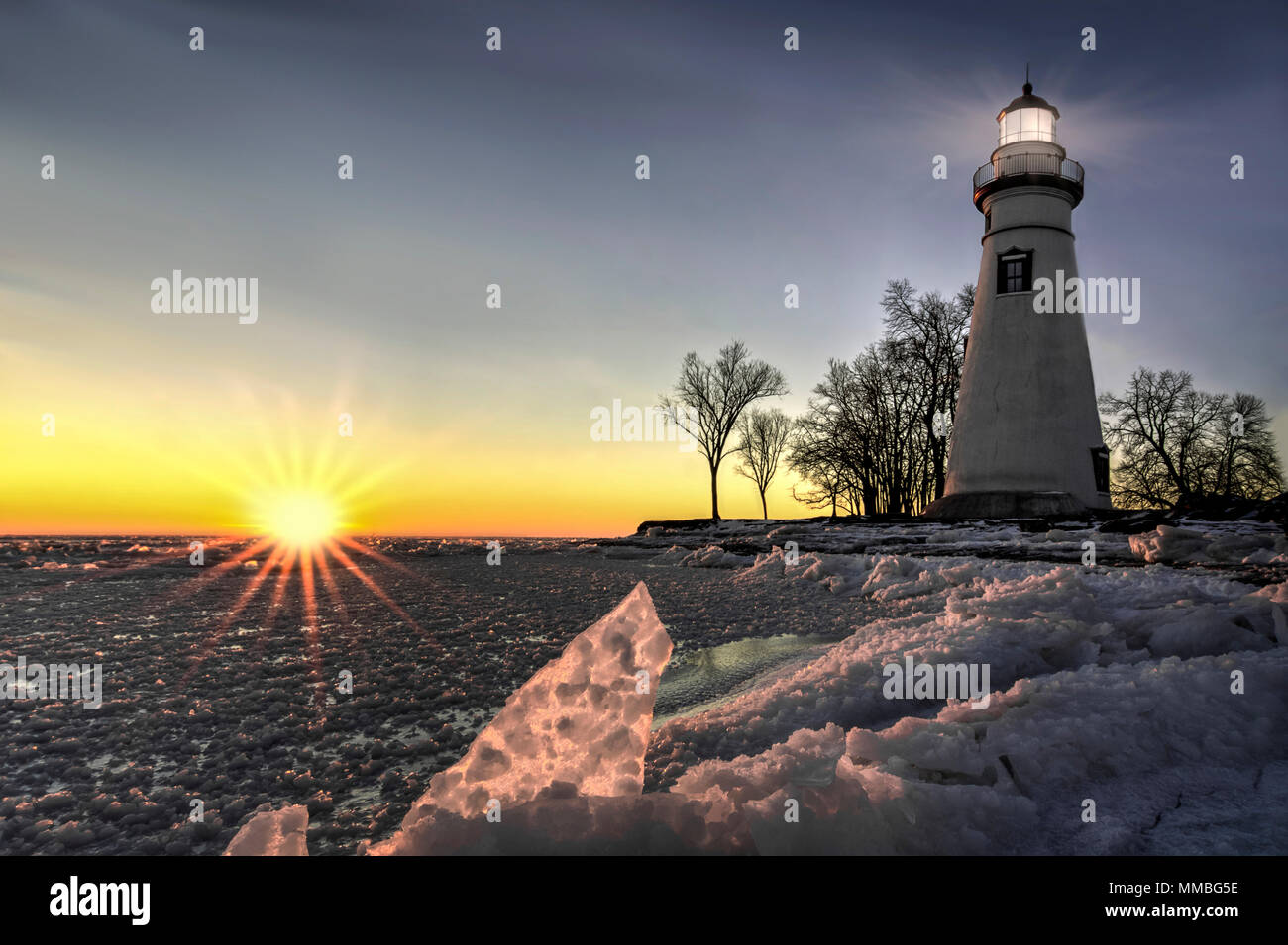 The historic Marblehead Lighthouse in Northwest Ohio sits along the rocky shores of Lake Erie. Seen here in winter at sunrise. Stock Photo