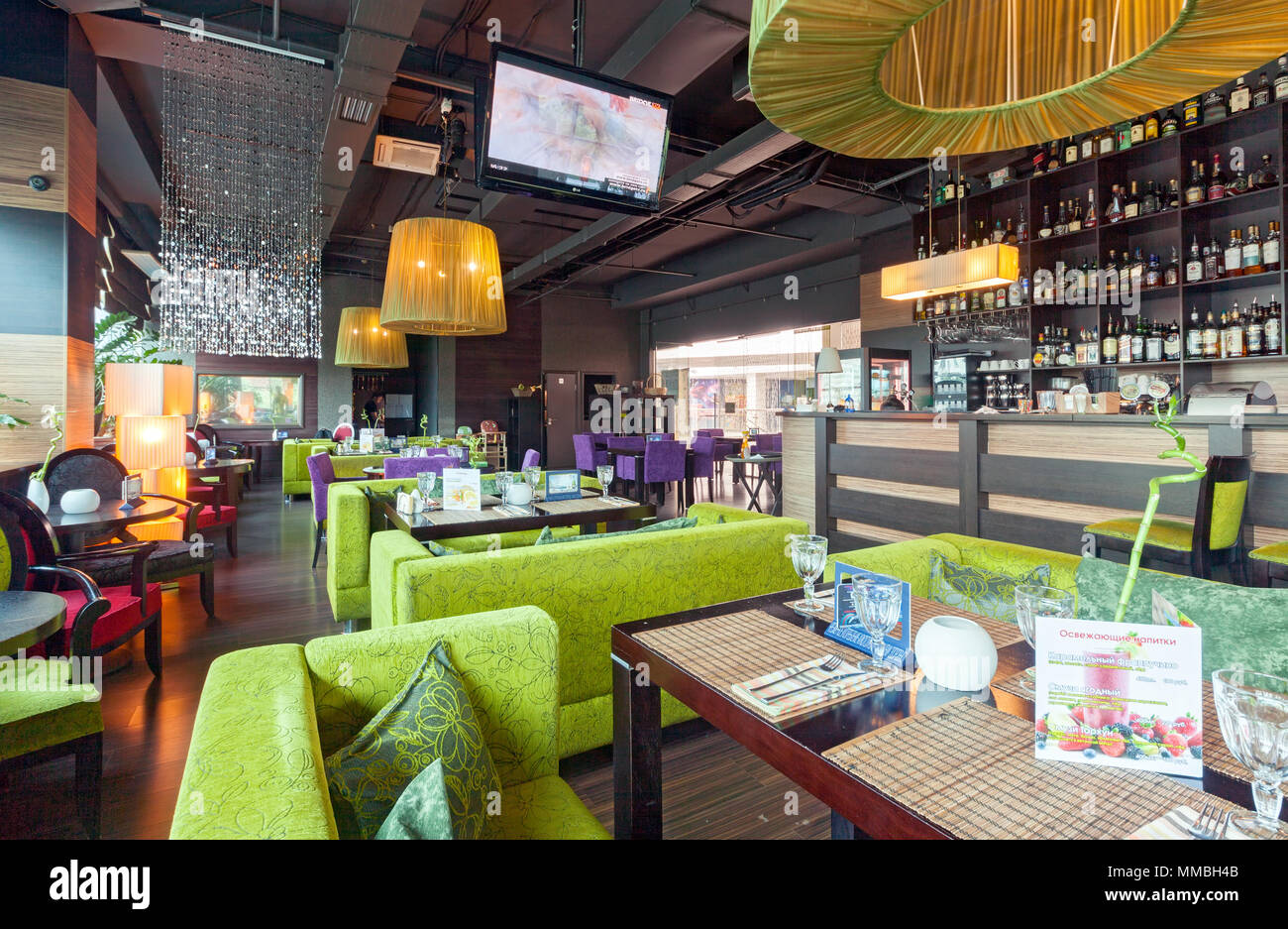 MOSCOW - AUGUST 2014: The interior of the bar restaurant 'GUAVA' in the modern and high-tech style. Tables and green couches next to the bar Stock Photo