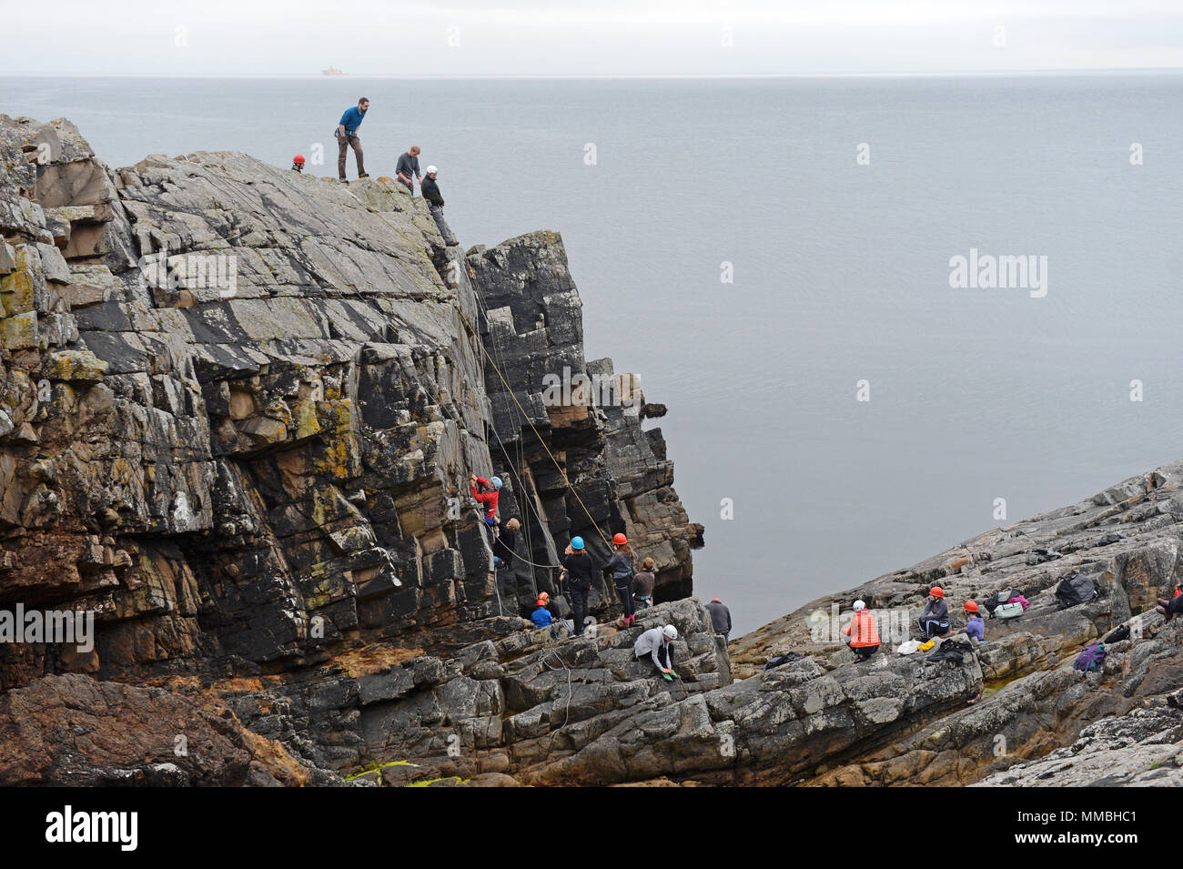 Climbers club climbing and abseiling on cliffs next to the sea. A