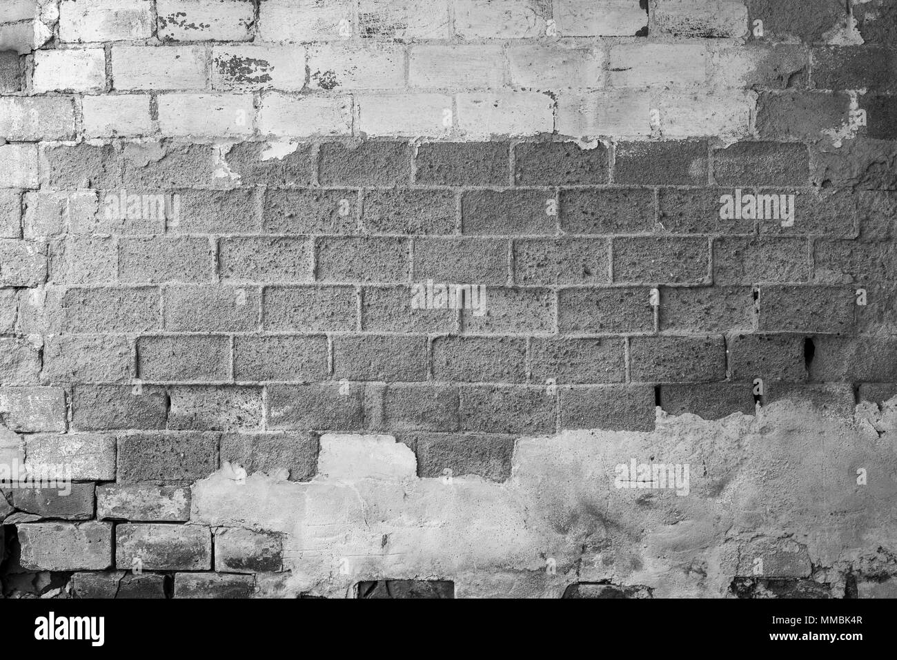 Full frame background of old and rough concrete block wall which is partly plastered or painted. Copy space. Black and white. Stock Photo