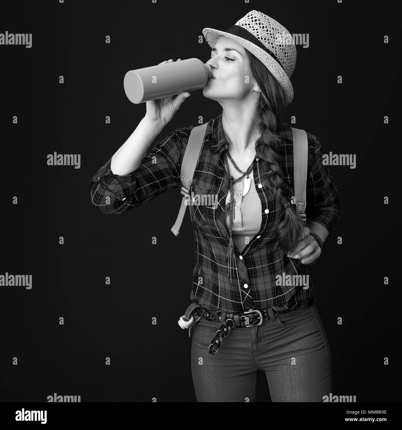 Searching for inspiring places. young traveller woman in a plaid shirt drinking water from bottle on background Stock Photo