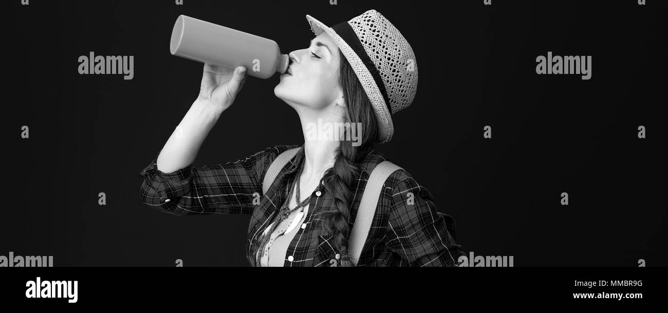Searching for inspiring places. fit tourist woman in a plaid shirt drinking water from bottle isolated on background Stock Photo