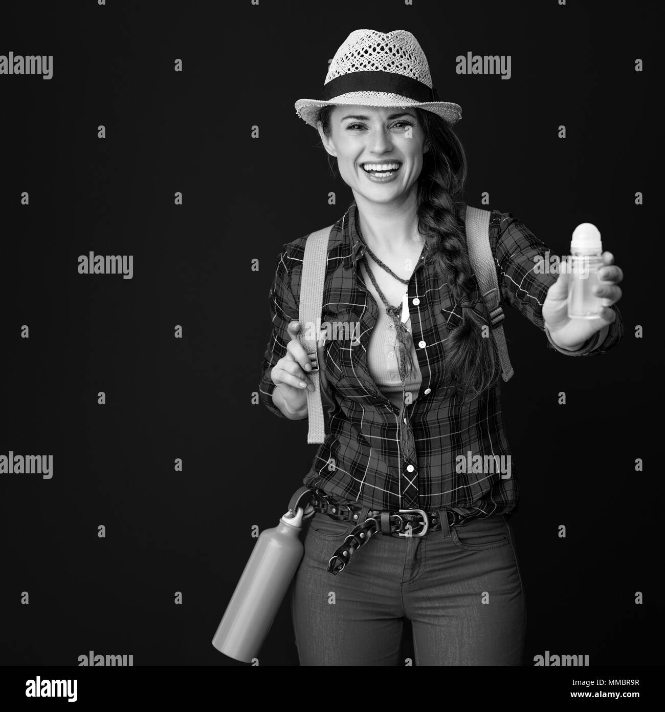 Searching for inspiring places. happy healthy tourist woman in a plaid shirt showing antiperspirant on background Stock Photo