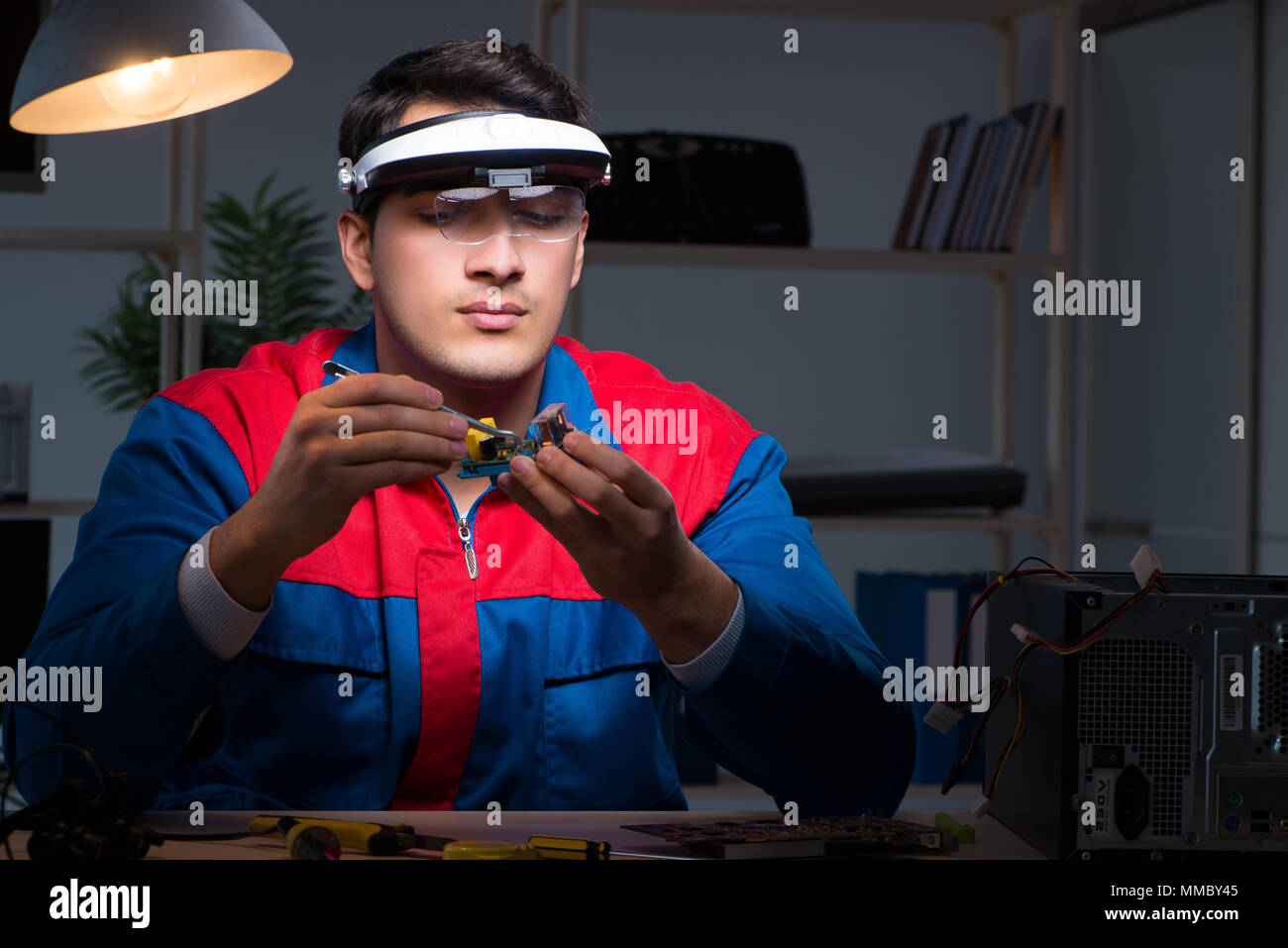 Computer specialist repairing PC late at night Stock Photo - Alamy