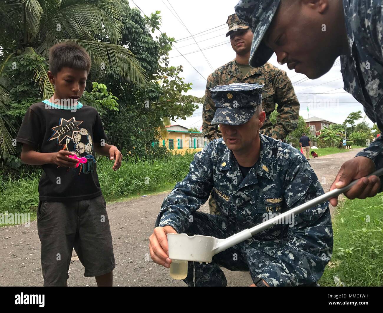171006-A-QE286-0032 PUERTO BARRIOS, Guatemala (Oct. 6, 2017) A local child watches Hospital Corpsman 1st Class Dominic Ladmirault, right, and Lt. Cmdr. Ian Sutherland, both assigned to Navy Entomology Center of Excellence, catch mosquito larvae at Clinico Salud Del Puerto Barrios, a local health clinic, during Southern Partnership Station 17 (SPS 17). SPS 17 is a U.S. Navy deployment executed by U.S. Naval Forces Southern Command/U.S. 4th Fleet, focused on subject matter expert exchanges with partner nation militaries and security forces in Central and South America. (U.S. Army photo by SPC Ju Stock Photo
