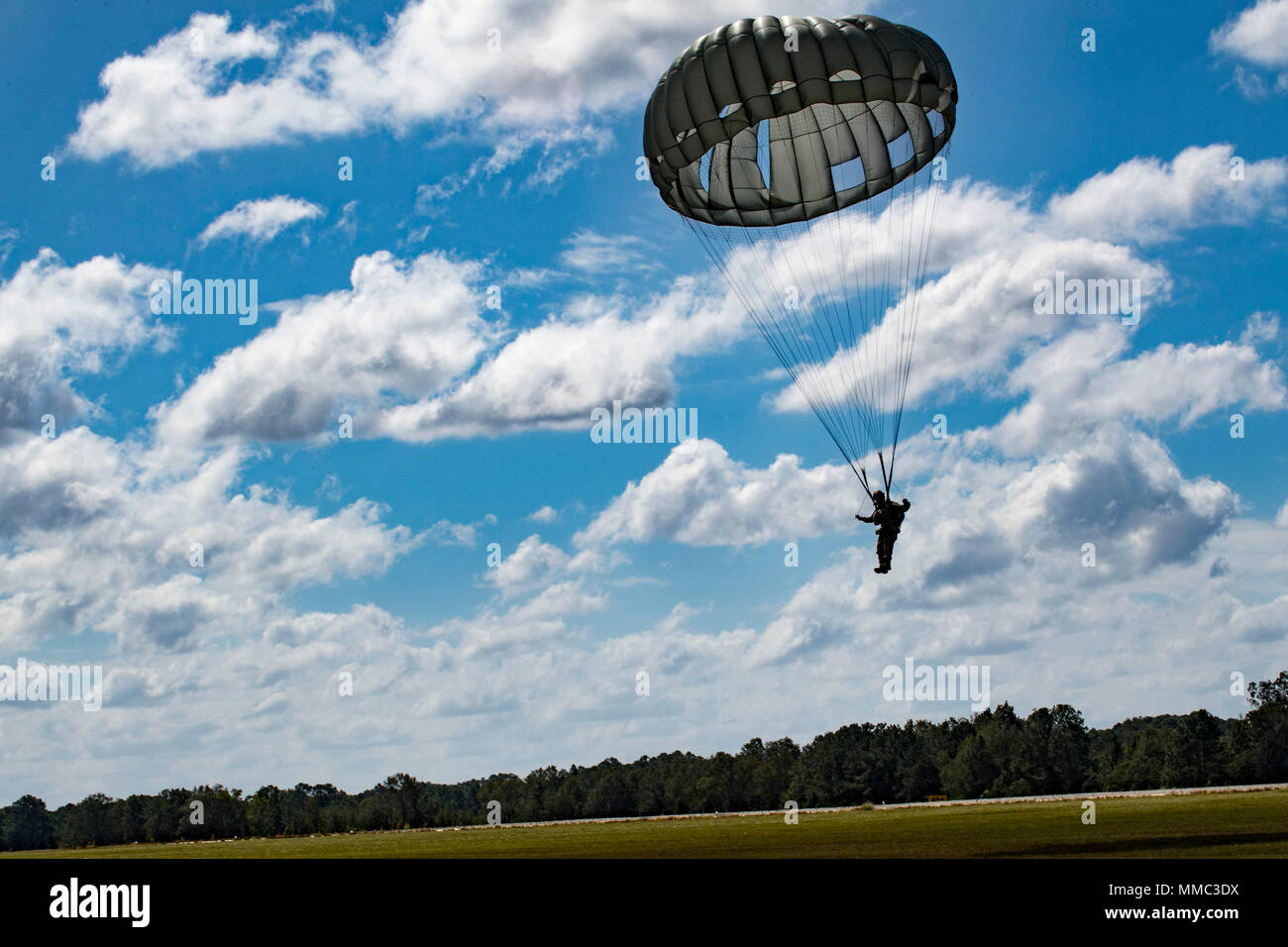 A member of the 820th Base Defense Group (BDG) descends during a static-line jump, Oct. 3, 2017, at the Lee Fulp drop zone in Tifton, Ga. The 820th Combat Operations Squadron’s four-person shop of parachute riggers are responsible for ensuring every 820th BDG parachute is serviceable, while also ensuring ground safety at the drop zone. The team has packed and inspected more than 490 parachutes in 2017. (U.S. Air Force photo by Airman 1st Class Daniel Snider) Stock Photo