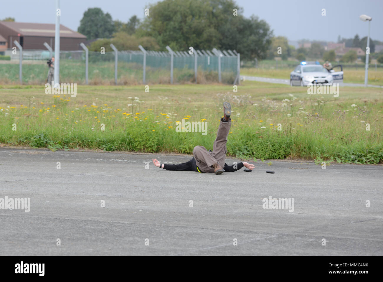 A role player falls on the ground and simulates being shot by the U.S. Army Military Police as U.S. Army Garrison Benelux holds Sentinel Shield 2017, a full scale exercise meant to test the collaboration between the garrison, tenant units and Belgian civilian agencies, on Chièvres Air Base, Belgium, Sep. 07, 2017. (U.S. Army photo by Visual Information Specialist Pierre-Etienne Courtejoie) Stock Photo