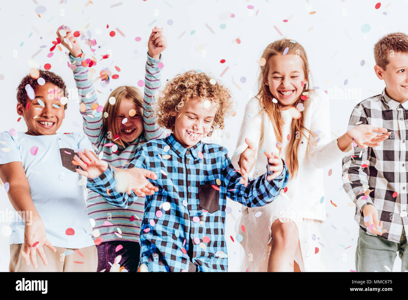 Happy kids throwing colorful confetti in a room Stock Photo Alamy