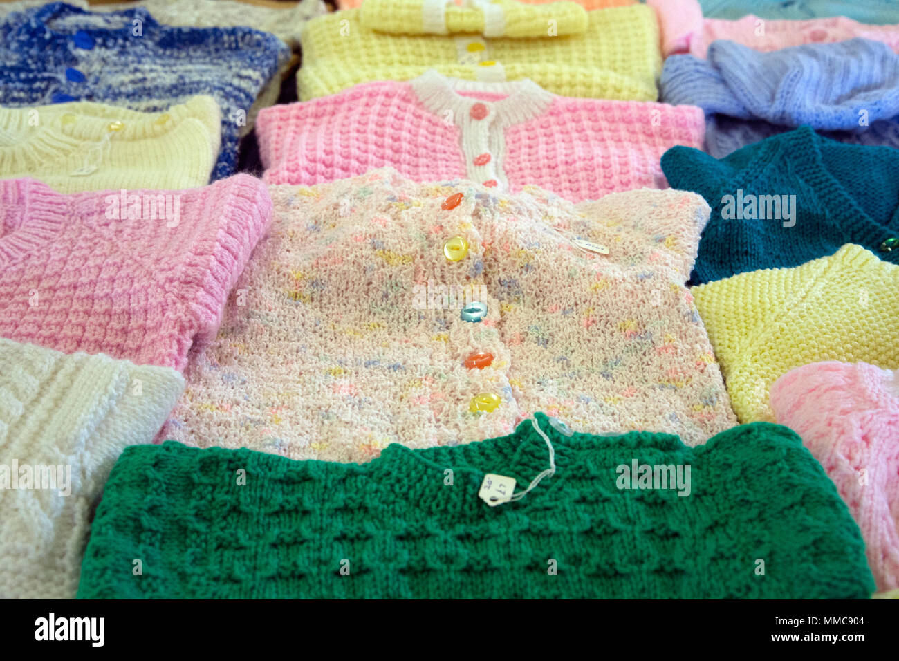 pristine new hand-knitted hand-made woollen cardigans and jumpers on sale in an english church hall fundraising for good causes for the parish council Stock Photo