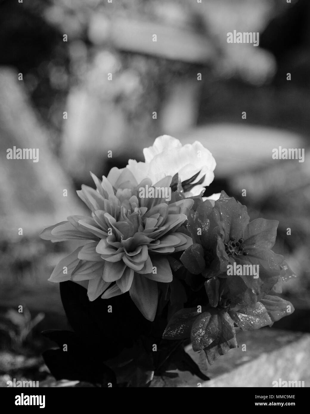 Artificial flowers decorate the grave of the dearly departed dead relative at London's famous Kensal Green Cemetery, sad funerals, dead people, black. Stock Photo