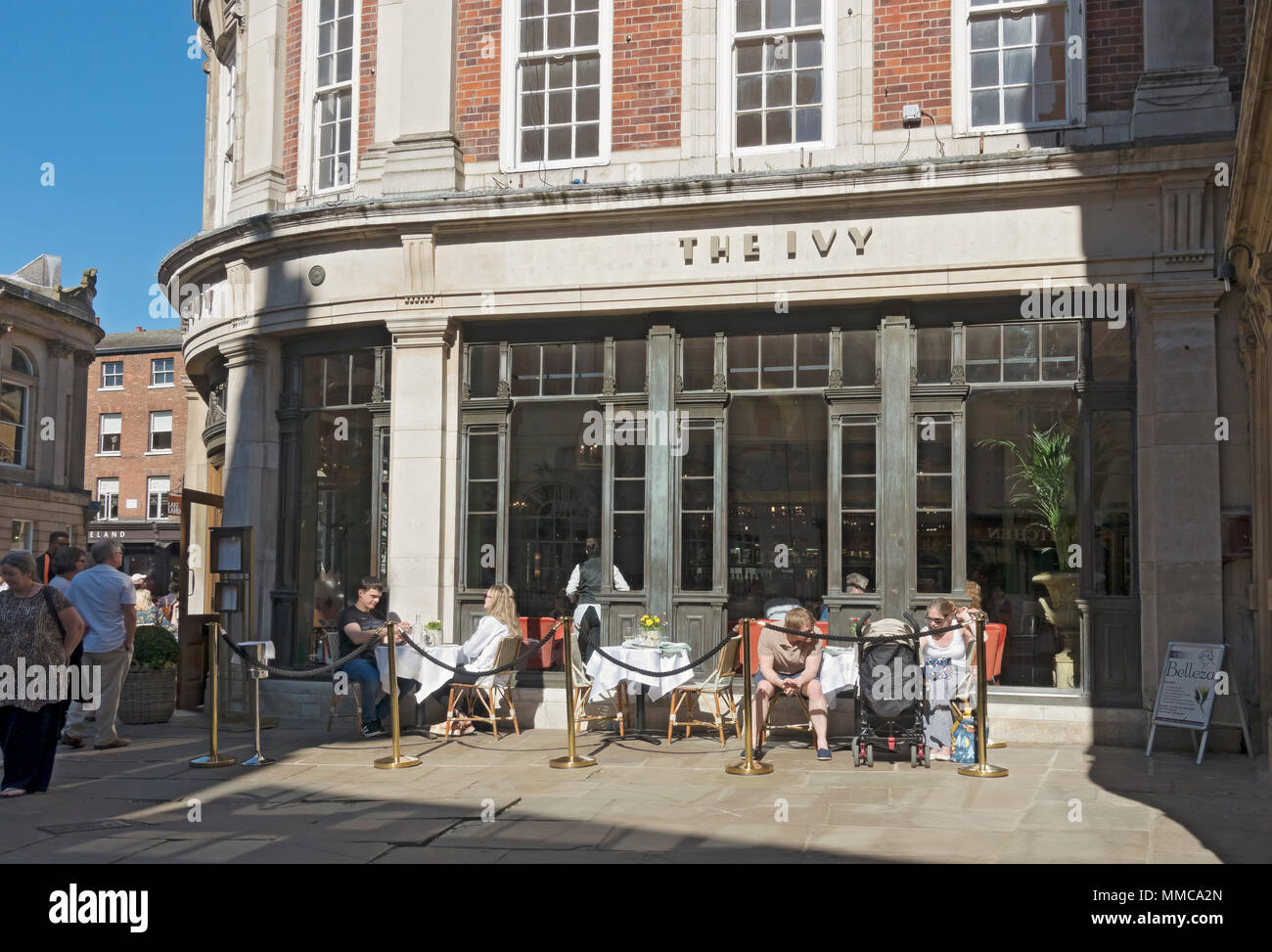 People sitting dining outside The Ivy restaurant in spring St Helens Square York city town Centre North Yorkshire England UK United Kingdom Britain Stock Photo