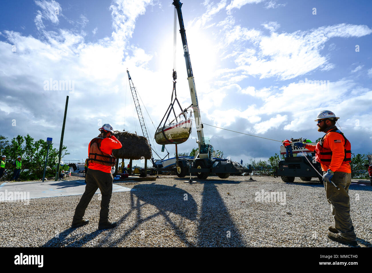Contractors hoist a vessel displaced by Hurricane Irma at Boot Key ...