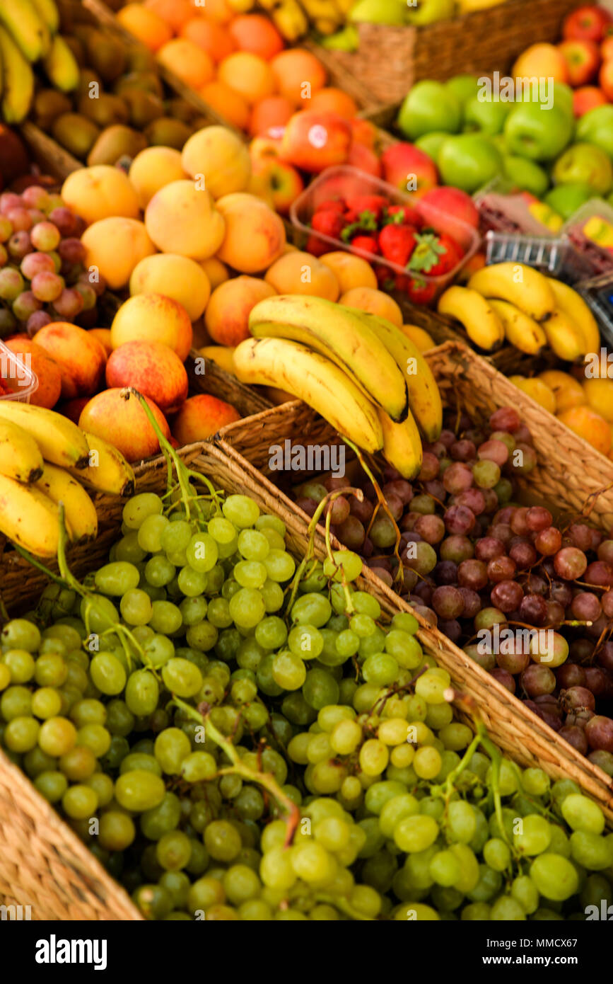 Close up of different exotic fruits at fairy at Ibiza island. Bananas, tangerines, pumpkin, grapes and peach. Eco and raw product for vega. Stock Photo