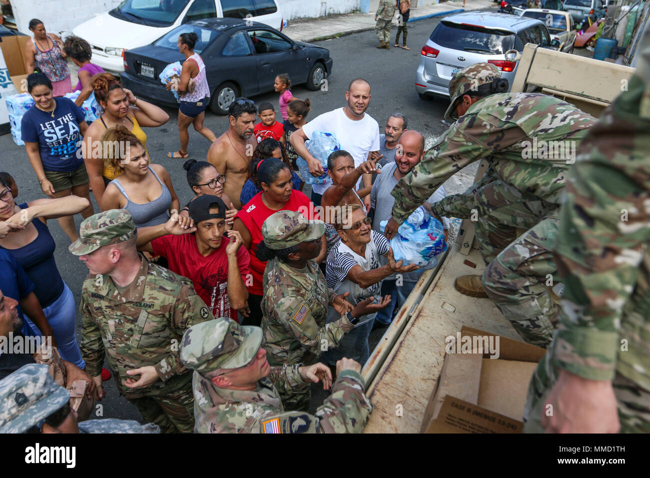 Master Sgt. Demel Anderson, a shower/laundry and clothing repair specialist assigned to the 3rd Expeditionary Sustainment Command, distributes water to a resident in the sector of Las Palmas in San Juan, Puerto Rico, October 12, 2017. The full force of the federal government continues to make progress towards recovery, working hand-in-hand with the U.S. Virgin Islands and Puerto Rico officials, municipalities, businesses and voluntary agencies on the islands. (U.S. Army photo by Sgt. 1st Class Donna Davis) Stock Photo