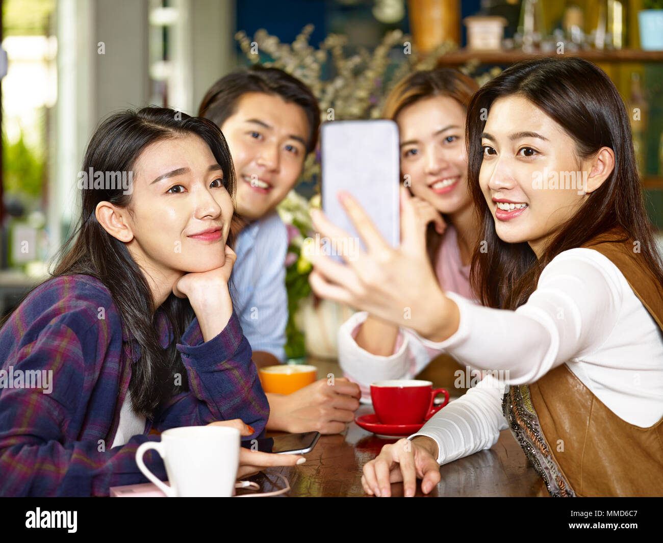 group of young asian adults man and women sitting coffee shop taking a selfie. Stock Photo