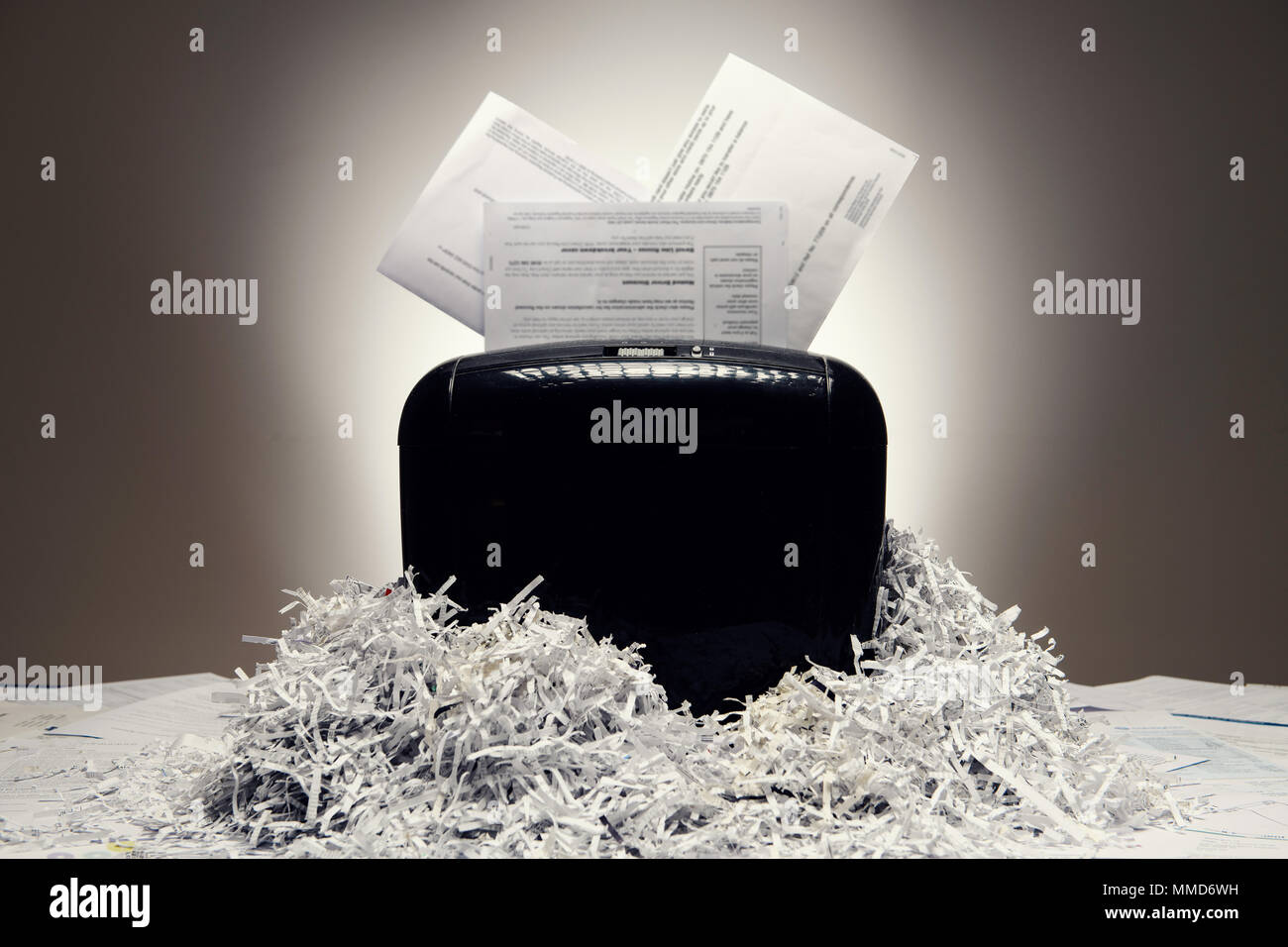 Office shredder and personal documents being shredded, with piles of shredded paper. Stock Photo