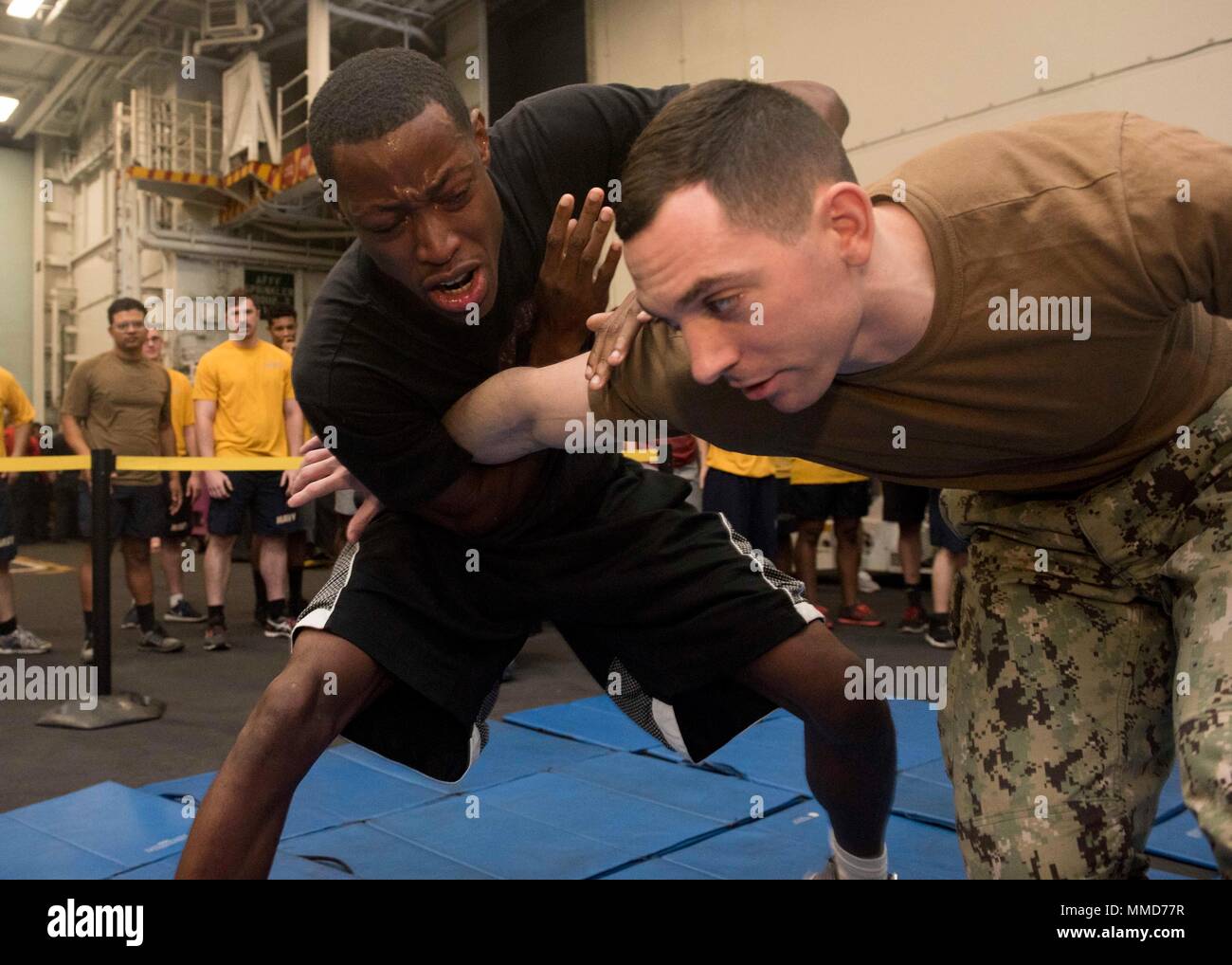 171018-N-YN937-152 ATLANTIC OCEAN (Oct. 18, 2017) Aviation Boatswain's Mate (Fuel) 3rd Class Antonio Perkins, left, performs a takedown on Master-at-Arms 2nd Class James Volponi during security reaction force training in the hangar bay aboard USS Harry S. Truman (CVN 75). Truman is currently underway conducting Tailored Shipboard Test Availability and Final Evaluation Problem (TSTA/FEP) in preparation for future operations. (U.S. Navy photo by Mass Communication Specialist 3rd Class Alan Lewis/Released) Stock Photo