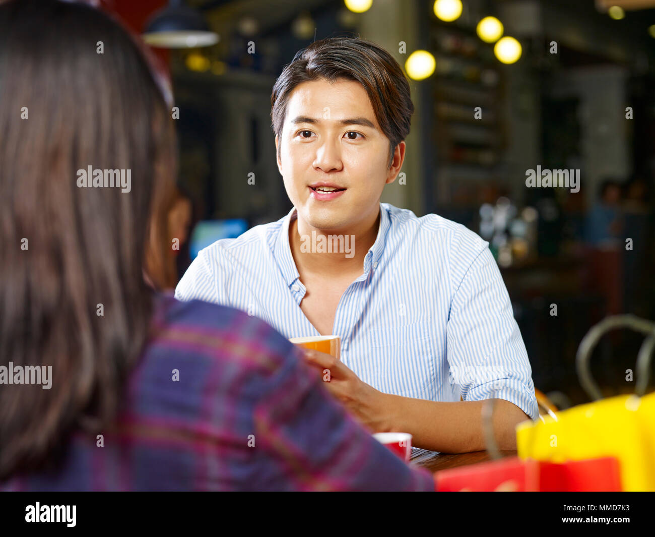 young asian couple lovers sitting chatting talking at table face to face in coffee shop. Stock Photo