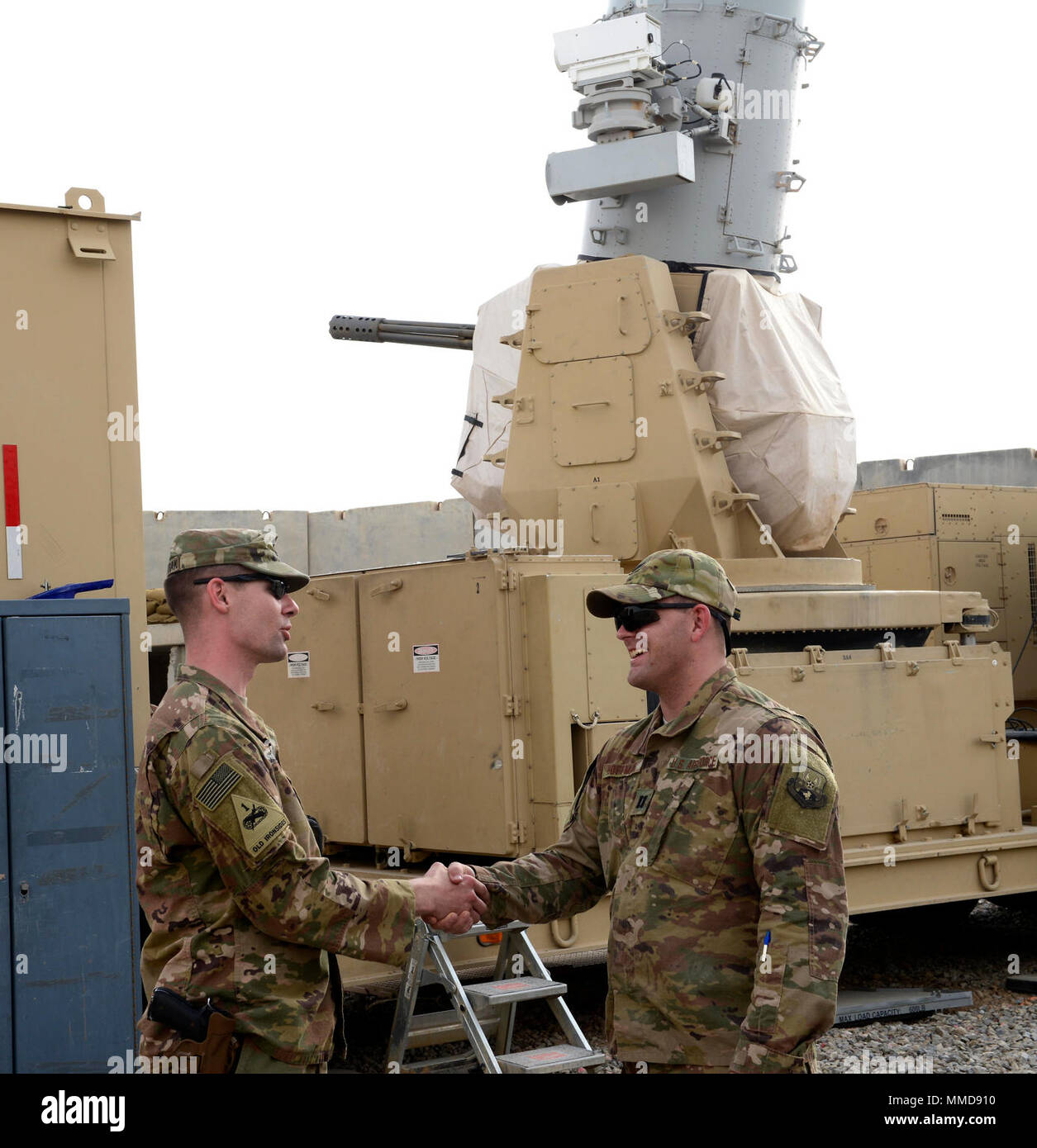 U.S. Army Capt. Eric Sylwestrak, battery commander, 2nd Battalion, 174th Air Defense Artillery Regiment, Ohio Army National Guard, shakes hands with U.S. Air Force Capt. Isaac Hoffman, project engineering officer-in-charge, 220th Engineering Installation Squadron, Ohio Air National Guard, in front of one of the Army's Counter-Rocket, Artillery, and Mortar (C-RAM) Intercept weapon systems at Kandahar Airfield, Afghanistan, March 10, 2018.  Airmen and Soldiers with both Ohio National Guard units worked together throughout a significant portion of their deployment during the past few months to co Stock Photo