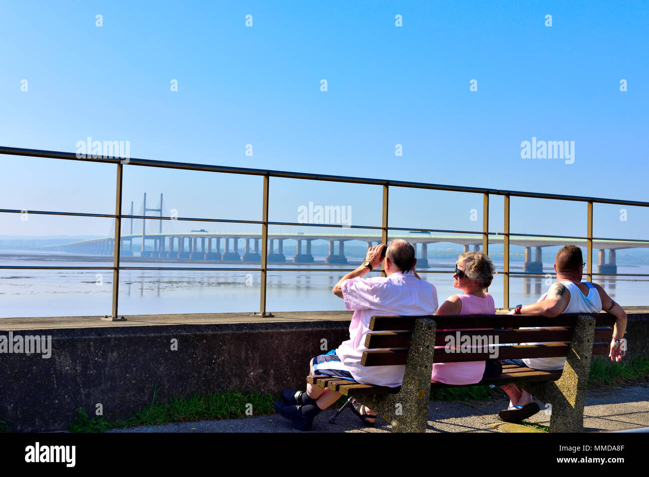 People on seat overlooking Severn Estuary with M4, Second Severn Crossing bridge Stock Photo