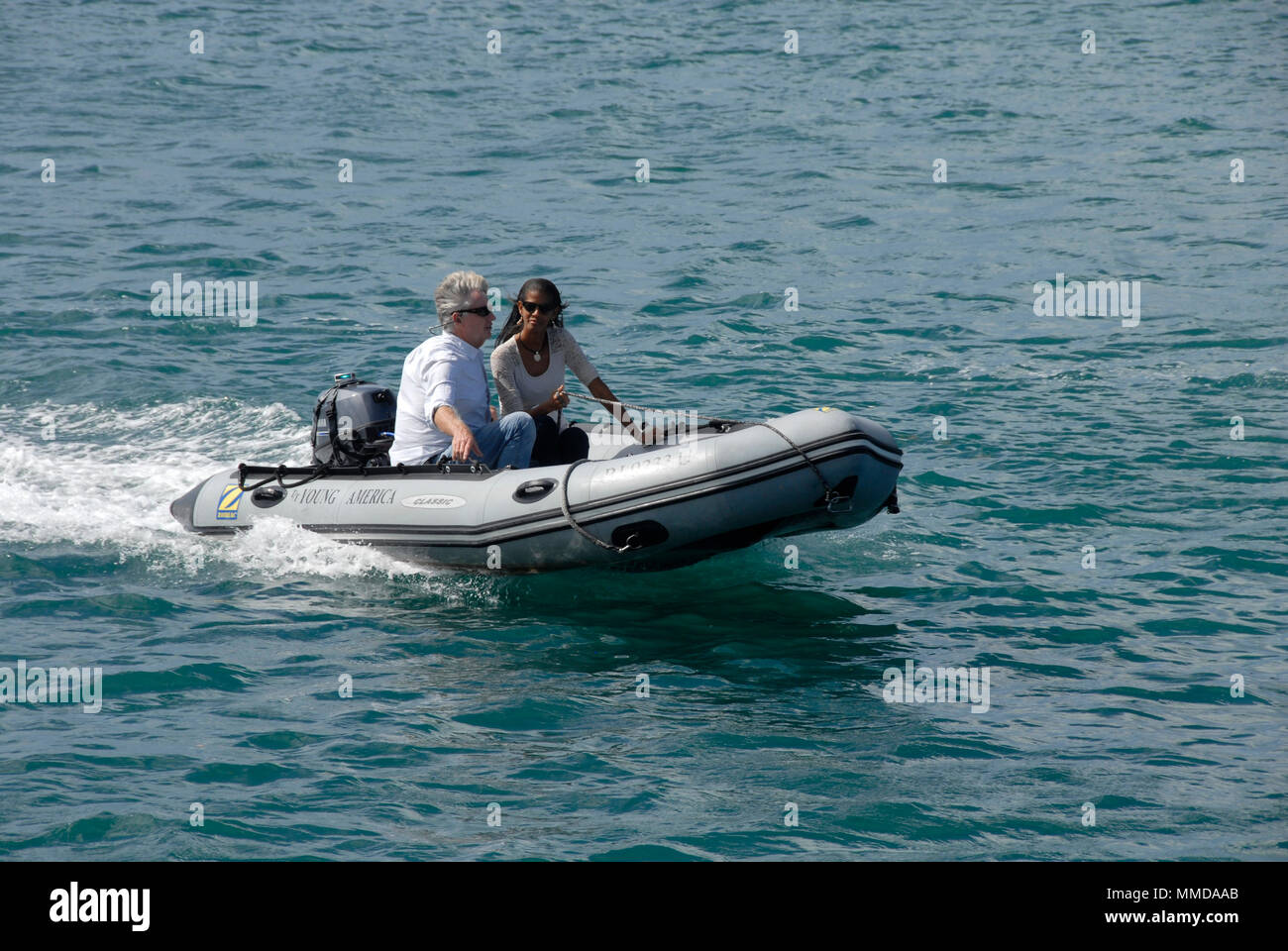 Couple in inflatable dinghy with outboard engine, Simpson's Bay, St Martin, Caribbean Stock Photo