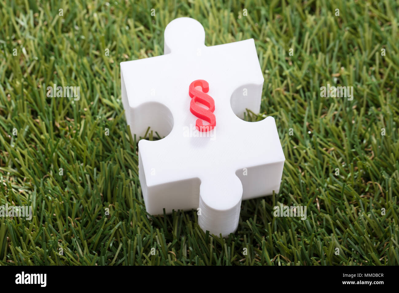 Elevated View Of Red Paragraph Symbol On White Jigsaw Puzzle Over Turf Stock Photo