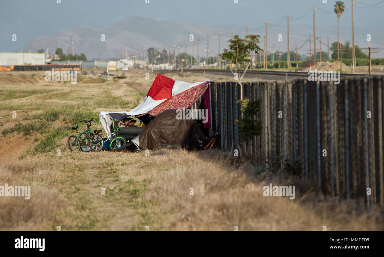 Homeless Camp against cyclone fence & railroad tracks. Stock Photo