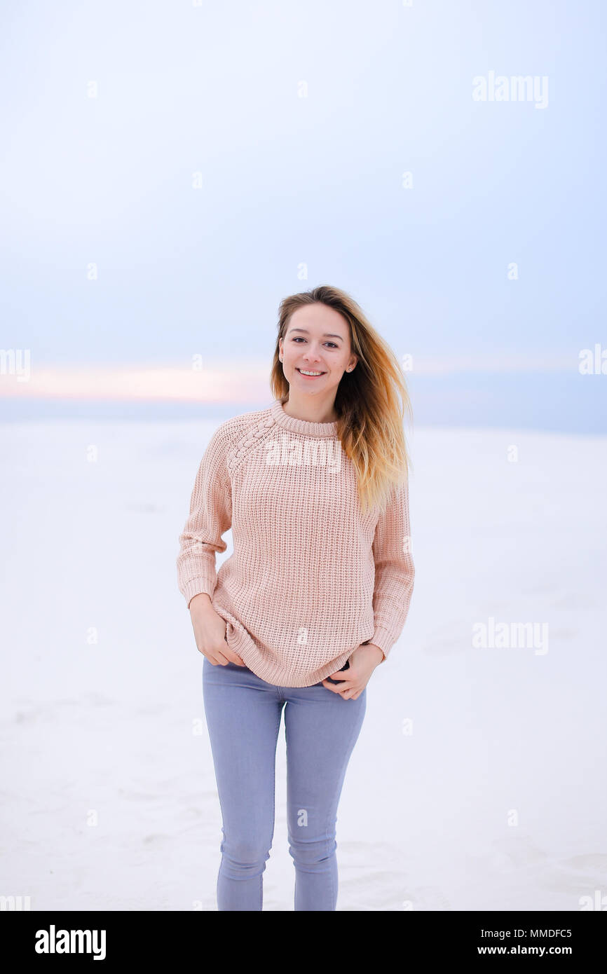 Happy girl wearing pink sweater and jeans standing in white winter  background Stock Photo - Alamy