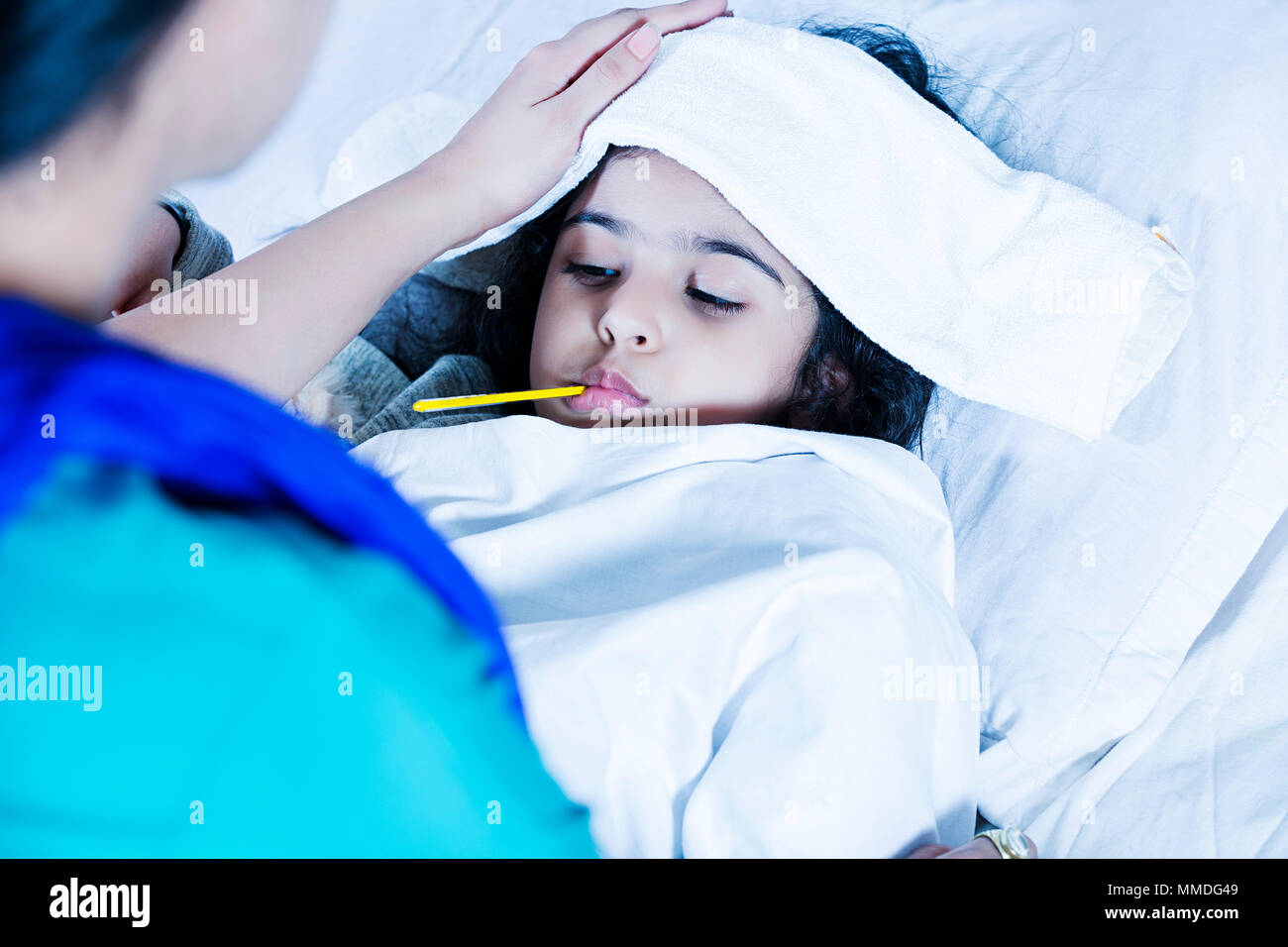 Sick Girl with thermometer laying-Bed And mother taking temperature Fever Stock Photo