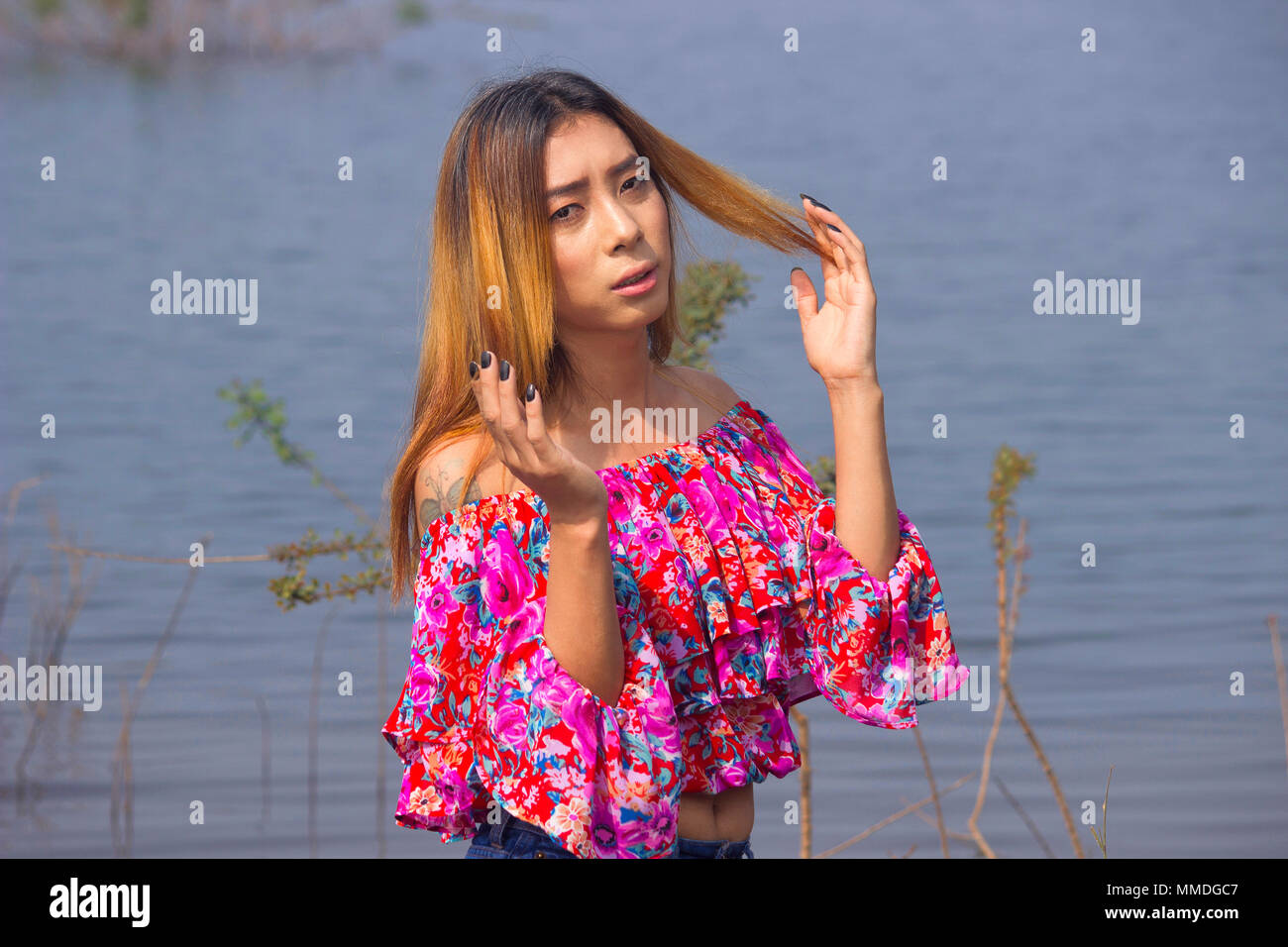 Stylish woman in floral top with raised hands Stock Photo