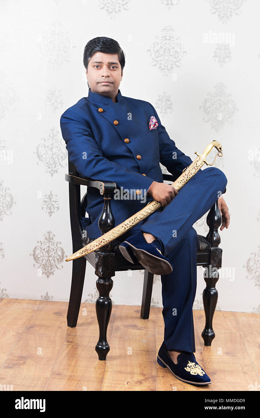 One Royal Rajasthani Man Sitting Chair Wearing Traditional-Dress With Sword Stock Photo