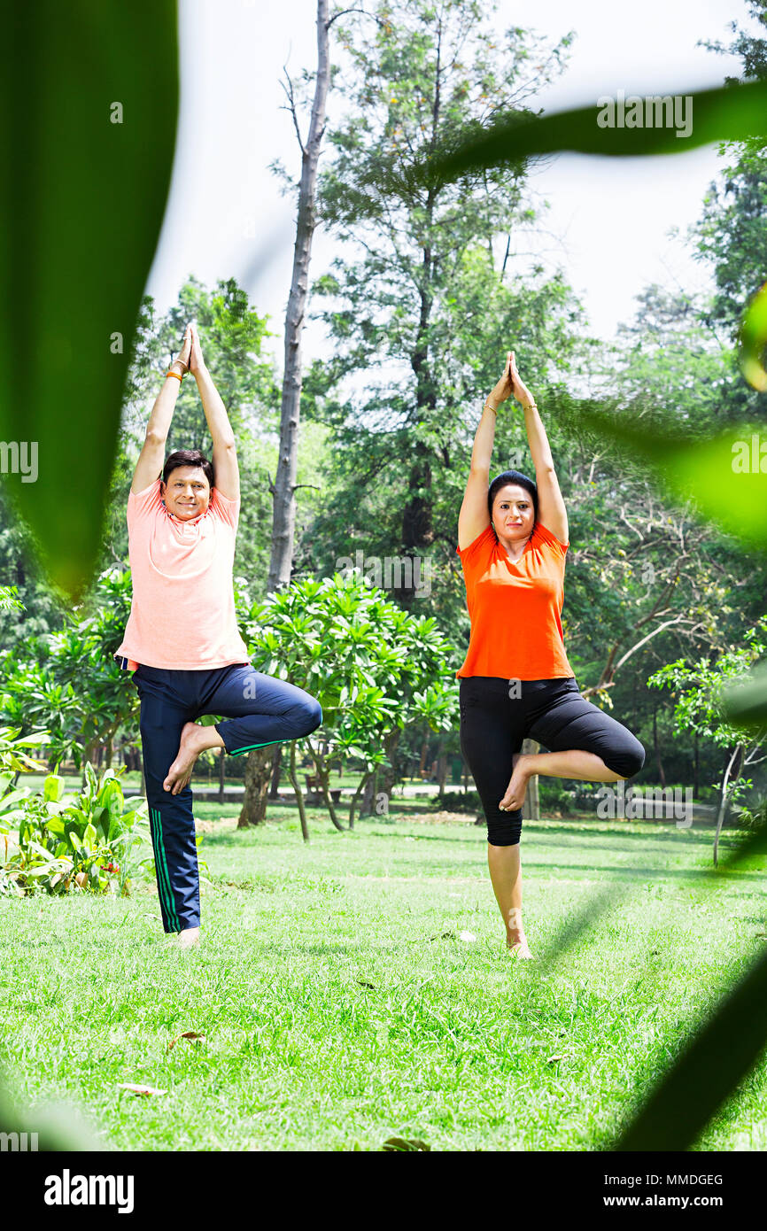 Two Couple Yoga Surya-Namaskar Meditating Standing-on-one-leg Morning Exercise Garden Stock Photo