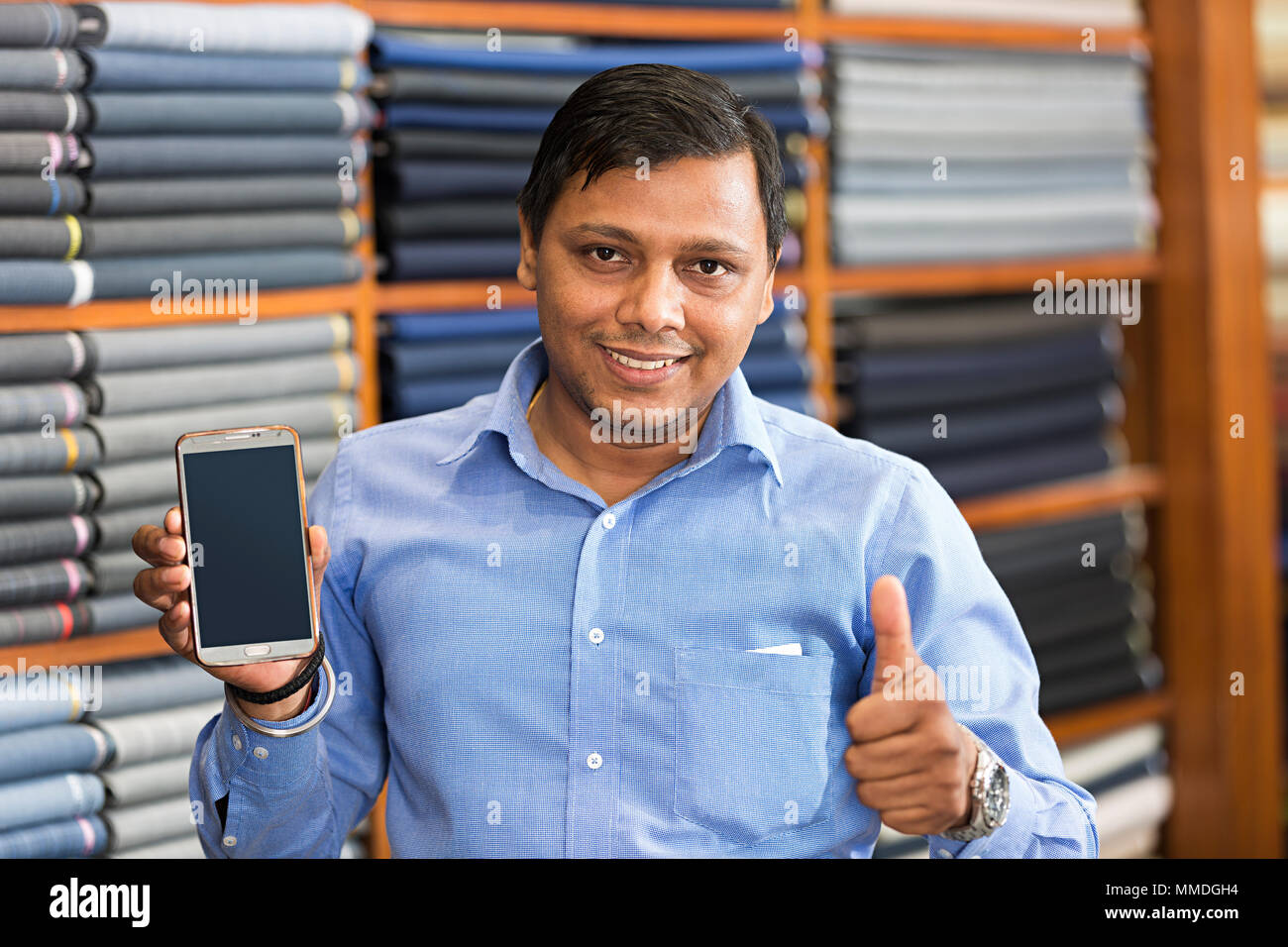 One Salesman Showing Thumbsup With Smart Phone In Clothes Store Stock