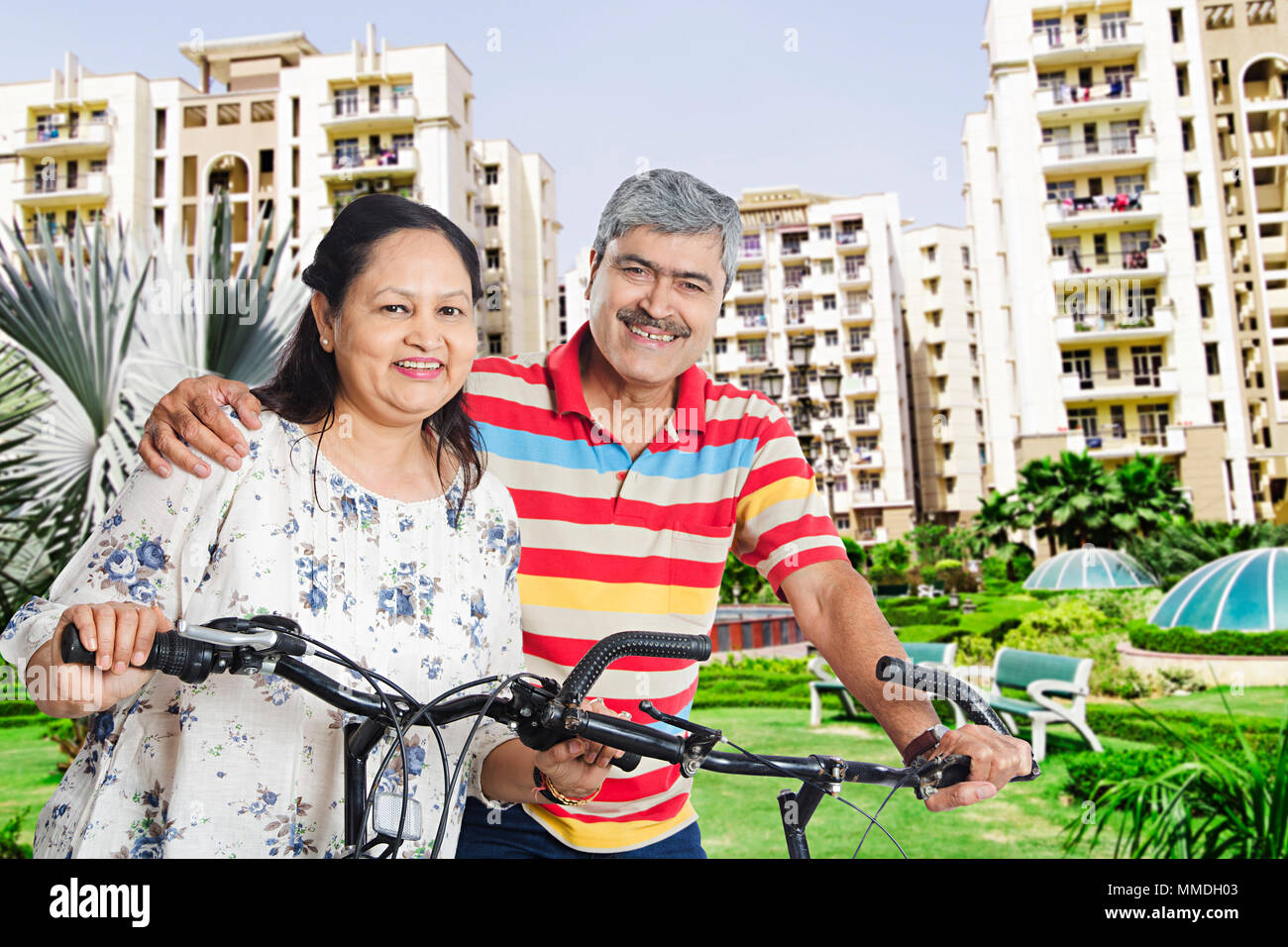 Happy Elderly Couple Ride Cycle Fun Enjoy In-Park Apartment House Stock Photo