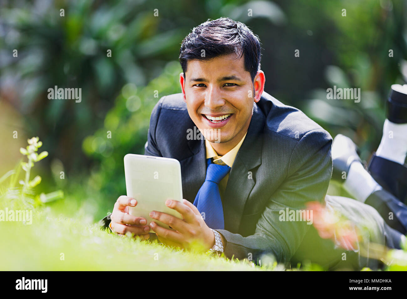 One Business Male Lying Grass Sending Text -Messaging Mobile Tablet-Pc Garden Stock Photo