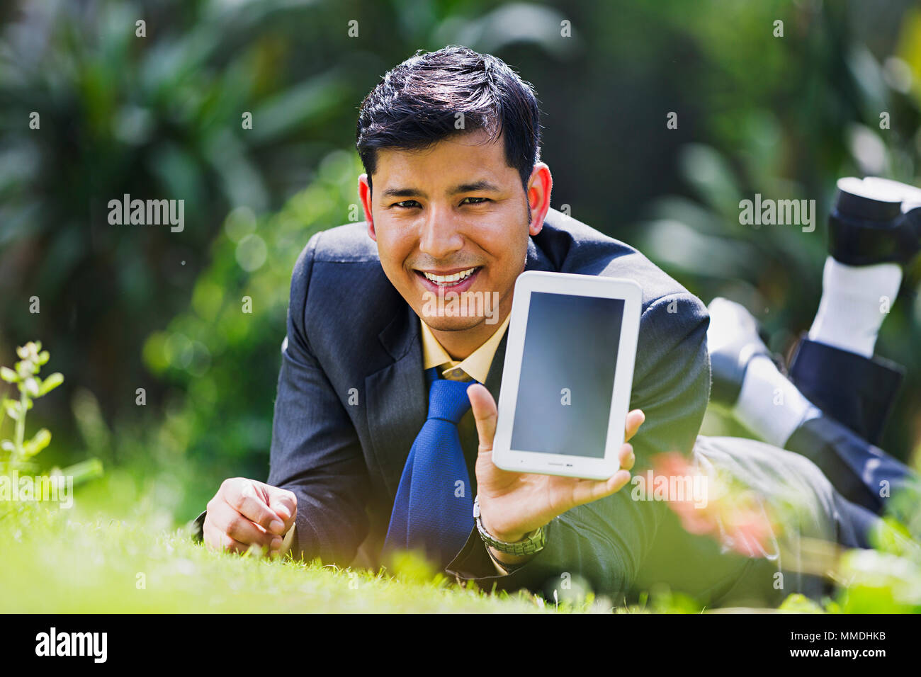 One Business Man Executive Lying Grass Showing Digital Tablet-Pc In-Garden Stock Photo