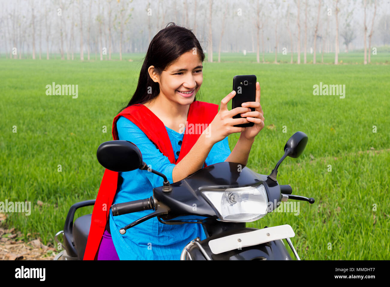 One Villager Teenage Girl Sitting Scooter, Reading Text-Message Mobile-Phone Farm Stock Photo