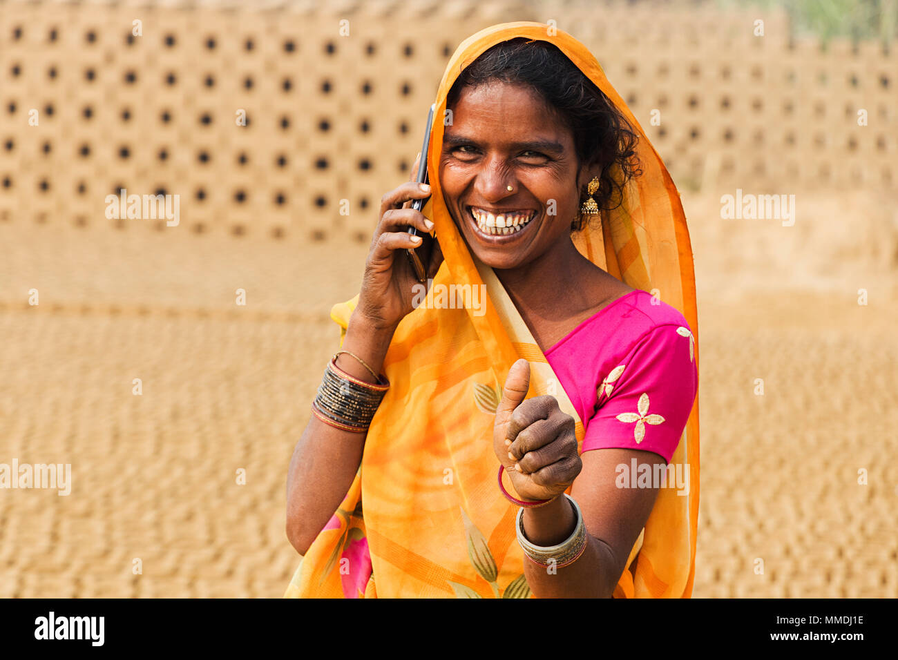 Rural Woman Labour Talking Cellphone And ShowingThumbs-up In Village Brick-Factory Stock Photo