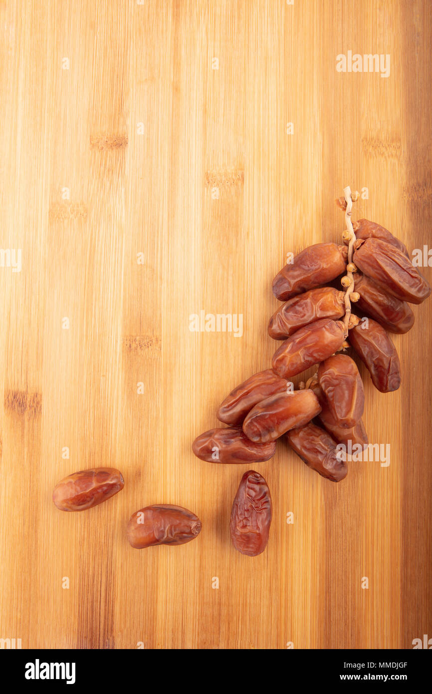 Branch of dried dates on a wooden background, fruits of date palm with