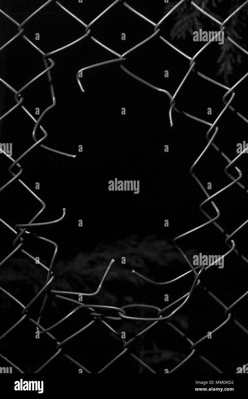 Ripped wire fence with black background. Stock Photo