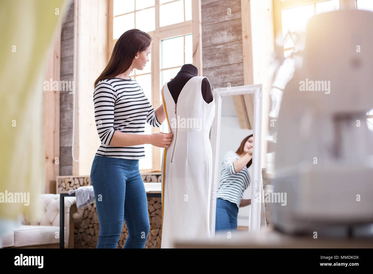 Focused female dressmaker tailoring dress Stock Photo