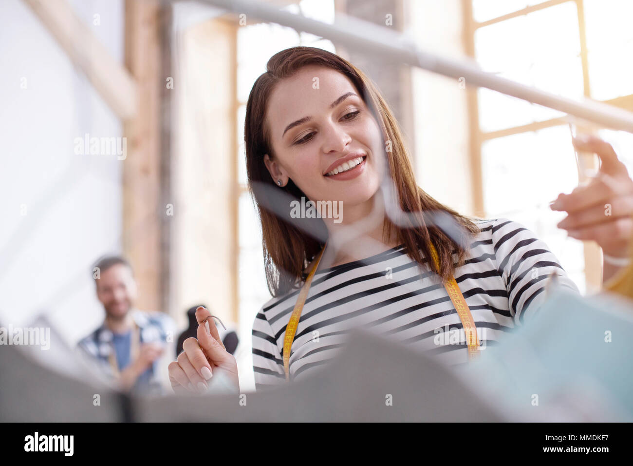 Reflective female stylist singling out garment Stock Photo