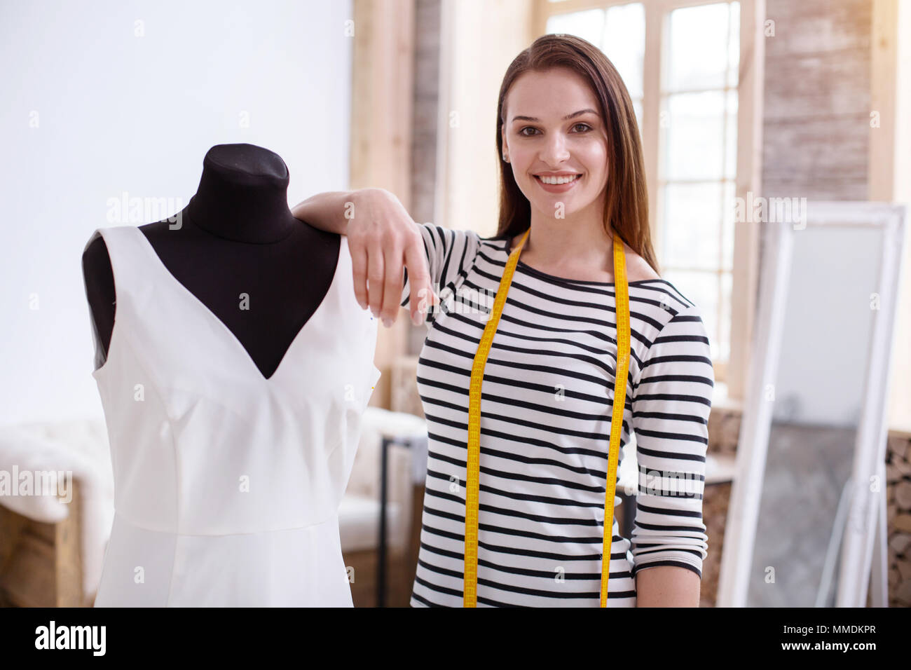 Confident female dressmaker showing dress Stock Photo