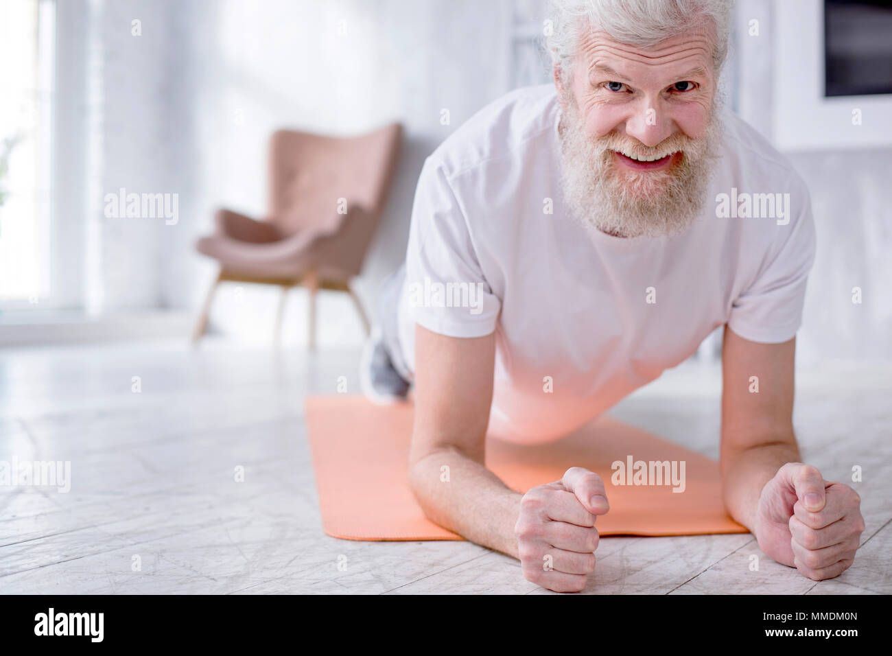 Charming senior man smiling while doing plank Stock Photo