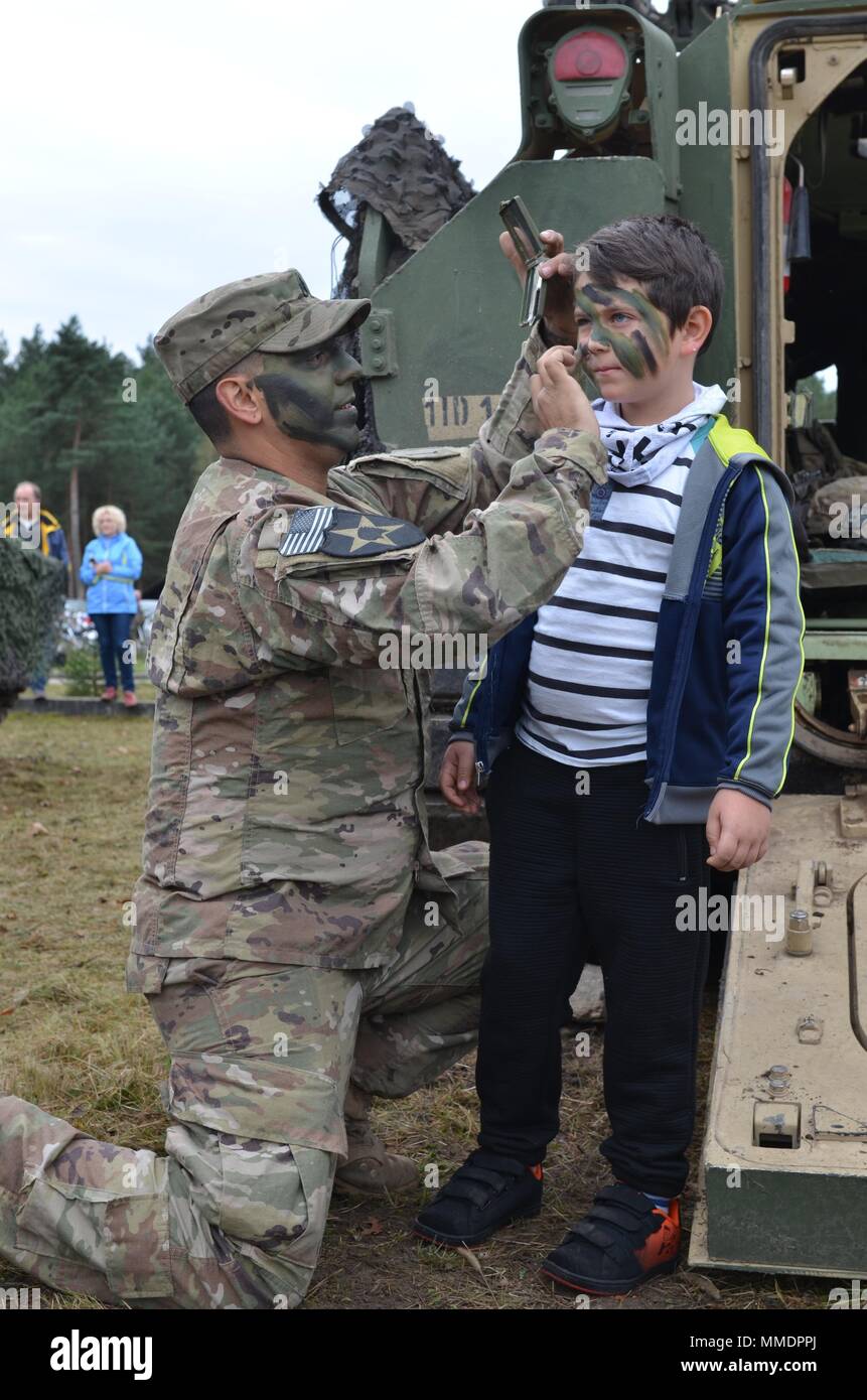 ZAGAN, Poland — U.S. Army Staff Sgt. Christian Duran, Cutthroat Company, 1st Battalion, 63 Armored Regiment, 2nd Armored Brigade Combat Team, 1st Infantry Division, applies camouflage to a volunteer during an Army display at the Museum of Prisoner of War Camps, Zagan, Poland, Oct. 21. The museum invites the unit to support Polish-American relations, history and education regarding the Stalag Luft III Prisoner Camp and World War II, since the unit was active in Europe during that time. The 2nd Armored Brigade Combat Team, 1st Infantry Division, is currently in Europe to support Atlantic Resolve Stock Photo