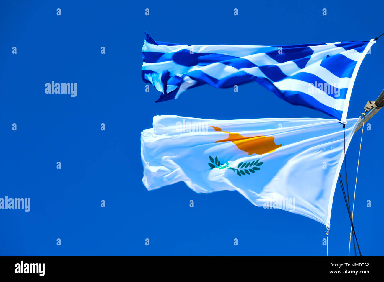 Waving Greek and Cyprian flags agaist the blue sky in strong wind with space for text Stock Photo