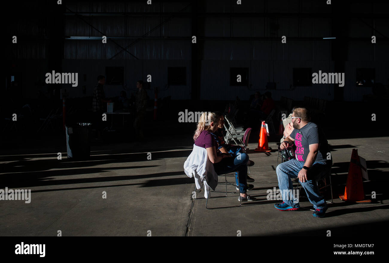 Families sit and wait in a hangar for their flights to begin during Spouses Day at Cannon Air Force Base, N.M., Oct. 21, 2017. Spouses Day gave servicemembers’ dependents the opportunity to experience how the Air Force mission runs at Cannon with demonstrations from units around the base. (U.S. Air Force photo by Senior Airman Lane T. Plummer) Stock Photo