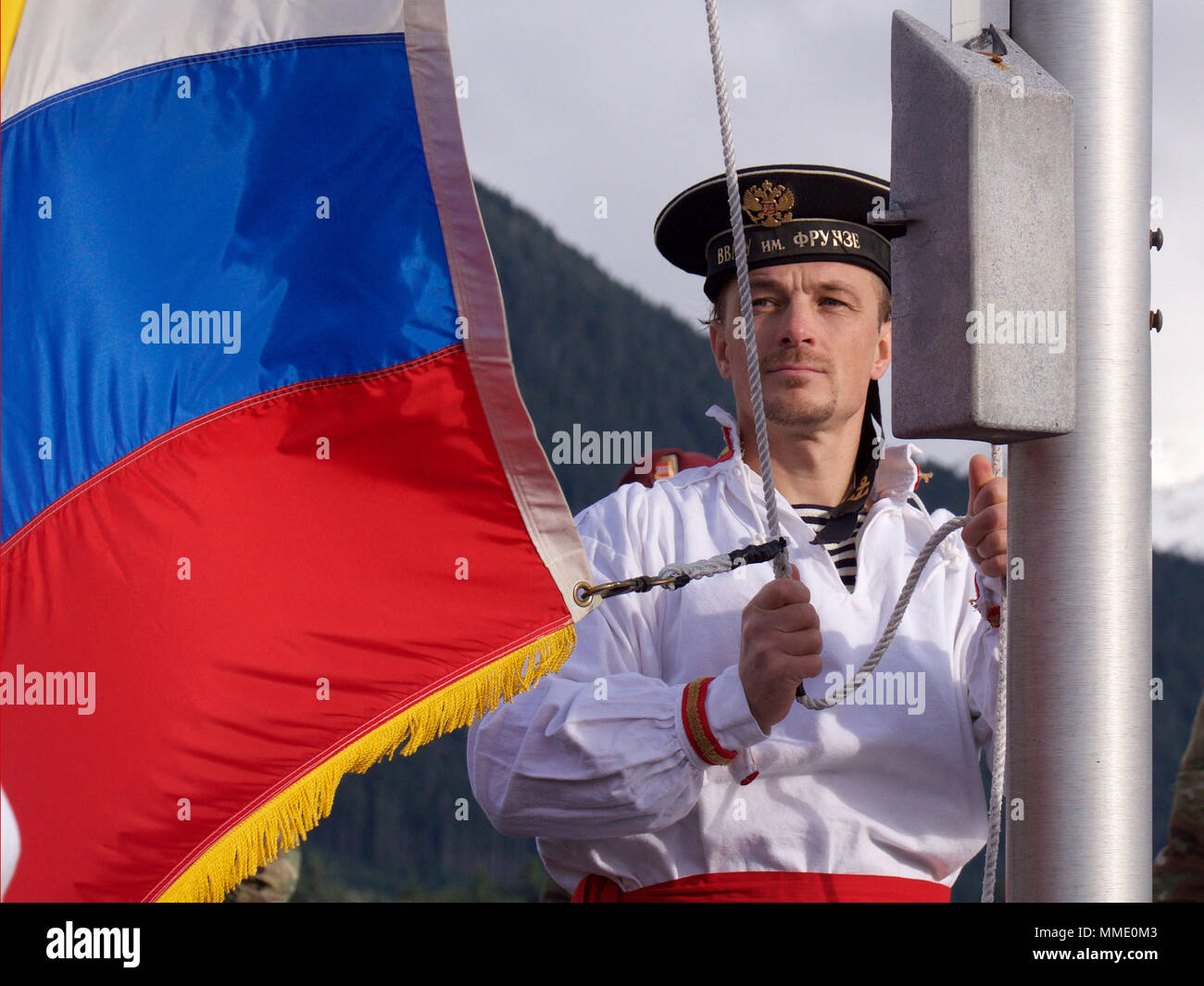 Roman Sorokin, portraying a Russian sailor, lowers the Russian flag at Castle Hill, Sitka, Alaska, during the Oct. 18, 2017, reenactment of the transfer of Alaska from Russia to the United States. This year marks 150 years since the Oct. 18, 1867, transfer ceremony. (U.S. Army National Guard photo by Sgt. David Bedard/released) Stock Photo