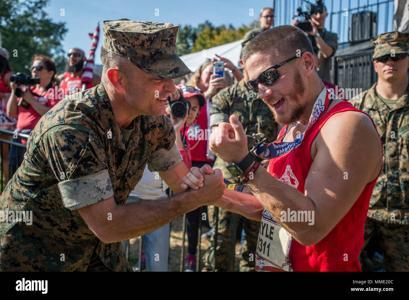 U.S. Marine Corps Col. Joseph Murray, left, commanding officer, Marine Corps Base Quantico, presents a  finisher medal to retired U.S. Marine Corps Cpl. Kyle Carpenter, Medal of Honor recipient, after crossing the finish line of the 42nd Marine Corps Marathon, Arlington, Va., Oct. 22, 2017. Also known as 'The People's Marathon,' the 26.2 mile race drew roughly 30,000 participants to promote physical fitness, generate goodwill in the community, and showcase the organizational skills of the Marine Corps. (U.S. Marine Corps photo by Lance Cpl. Yasmin D. Perez) Stock Photo